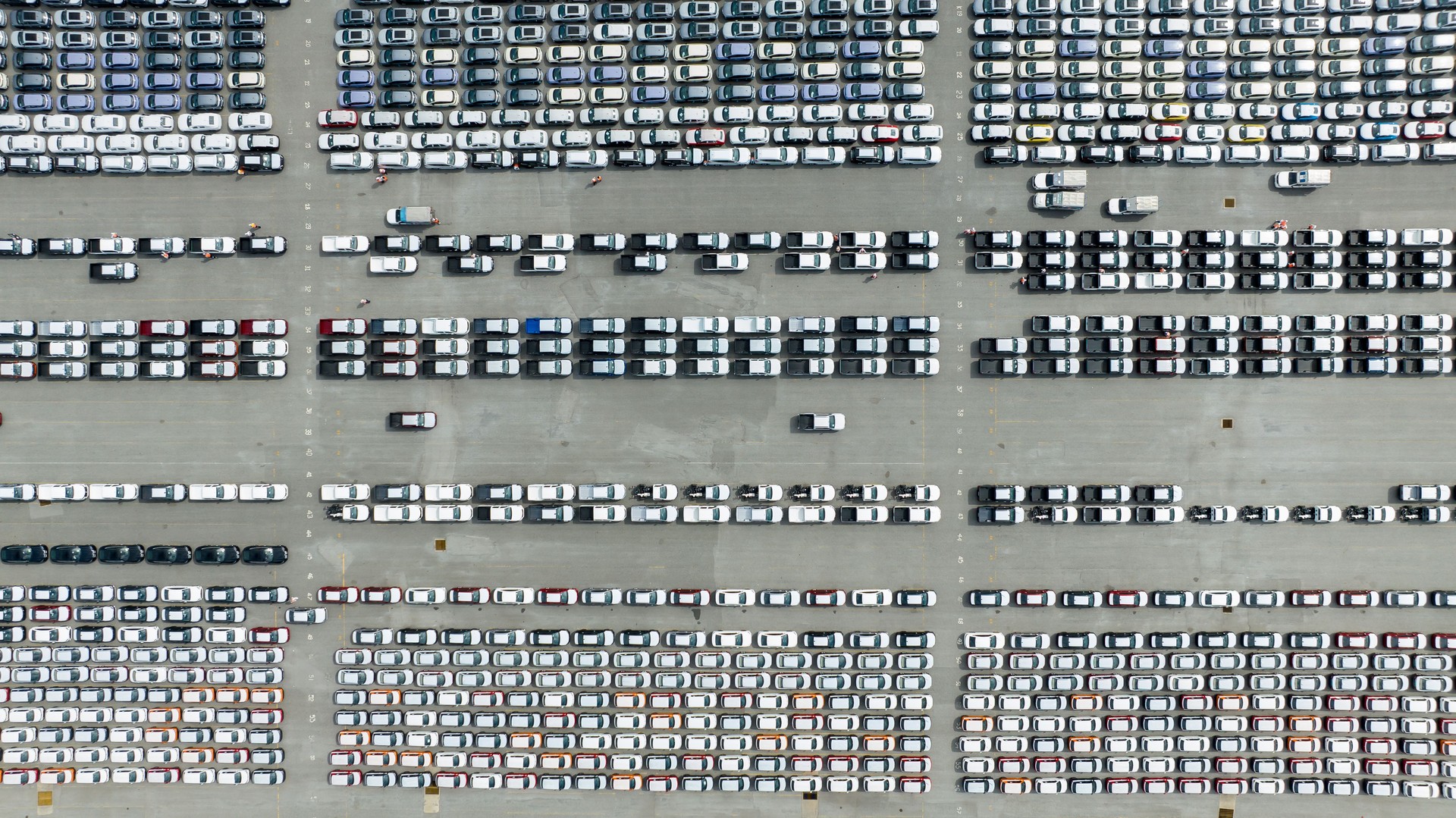 Aerial top view new cars lined up in the factory and commercial port for export international by container ship transport  in open sea,